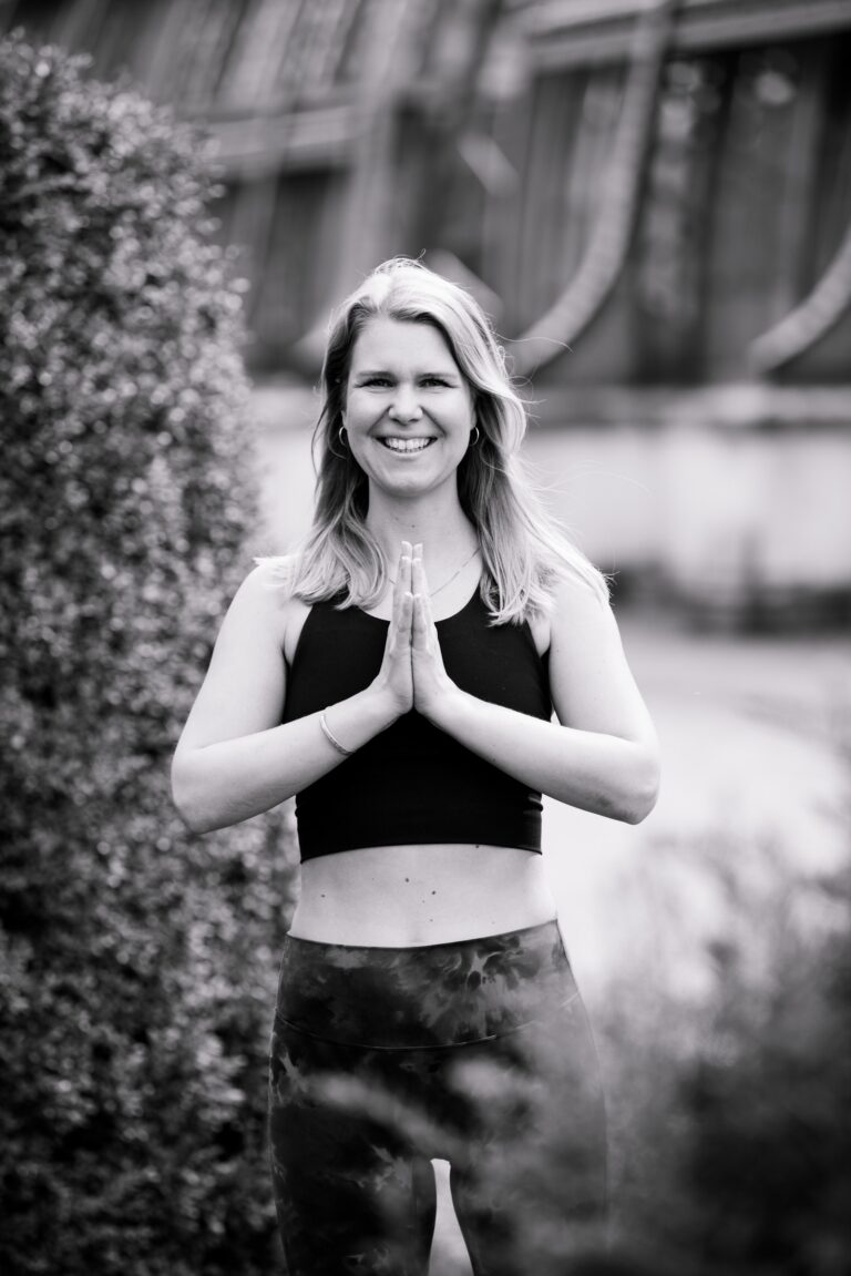 Eine Frau hält die Hände in Anjali Mudra. Eine grüßende Geste im Yoga.